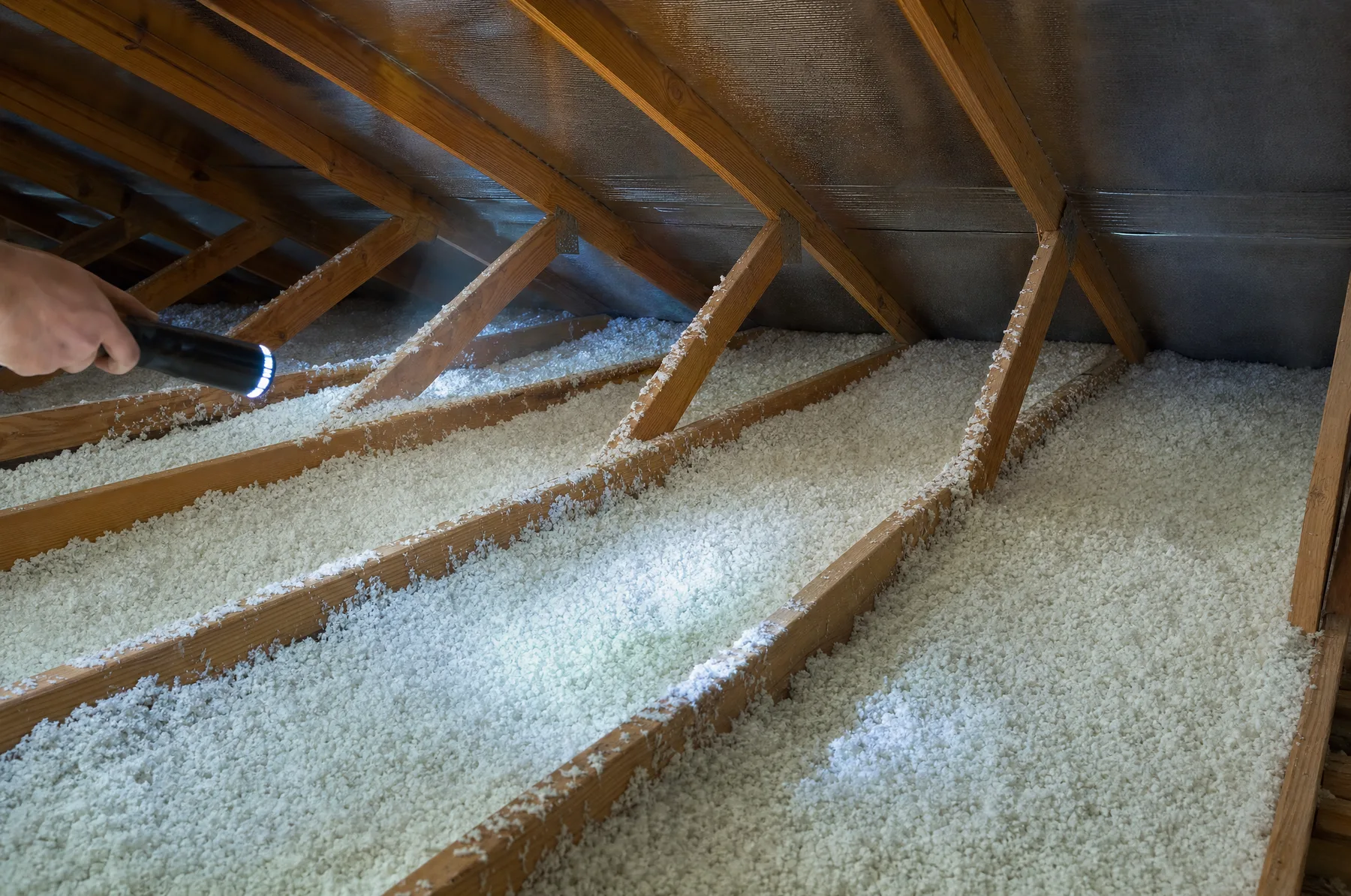 Ático de una casa con aislamiento soplado entre las vigas y barrera radiante bajo el techo